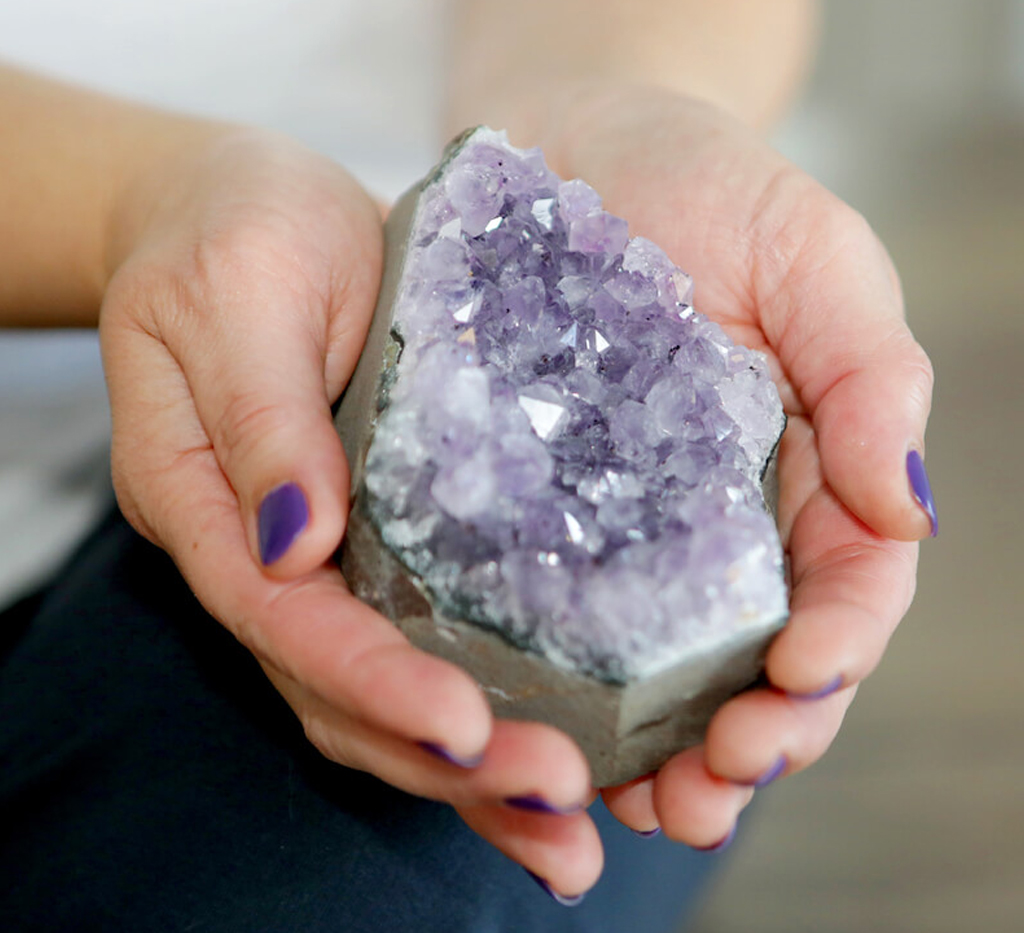 Cupped hand holding an amethyst crystal